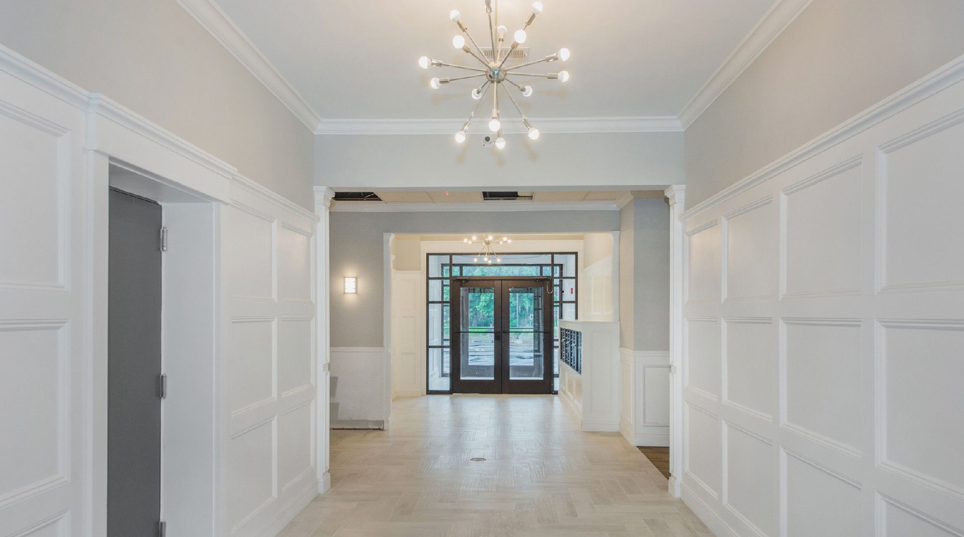 A large hallway with two doors and a chandelier.